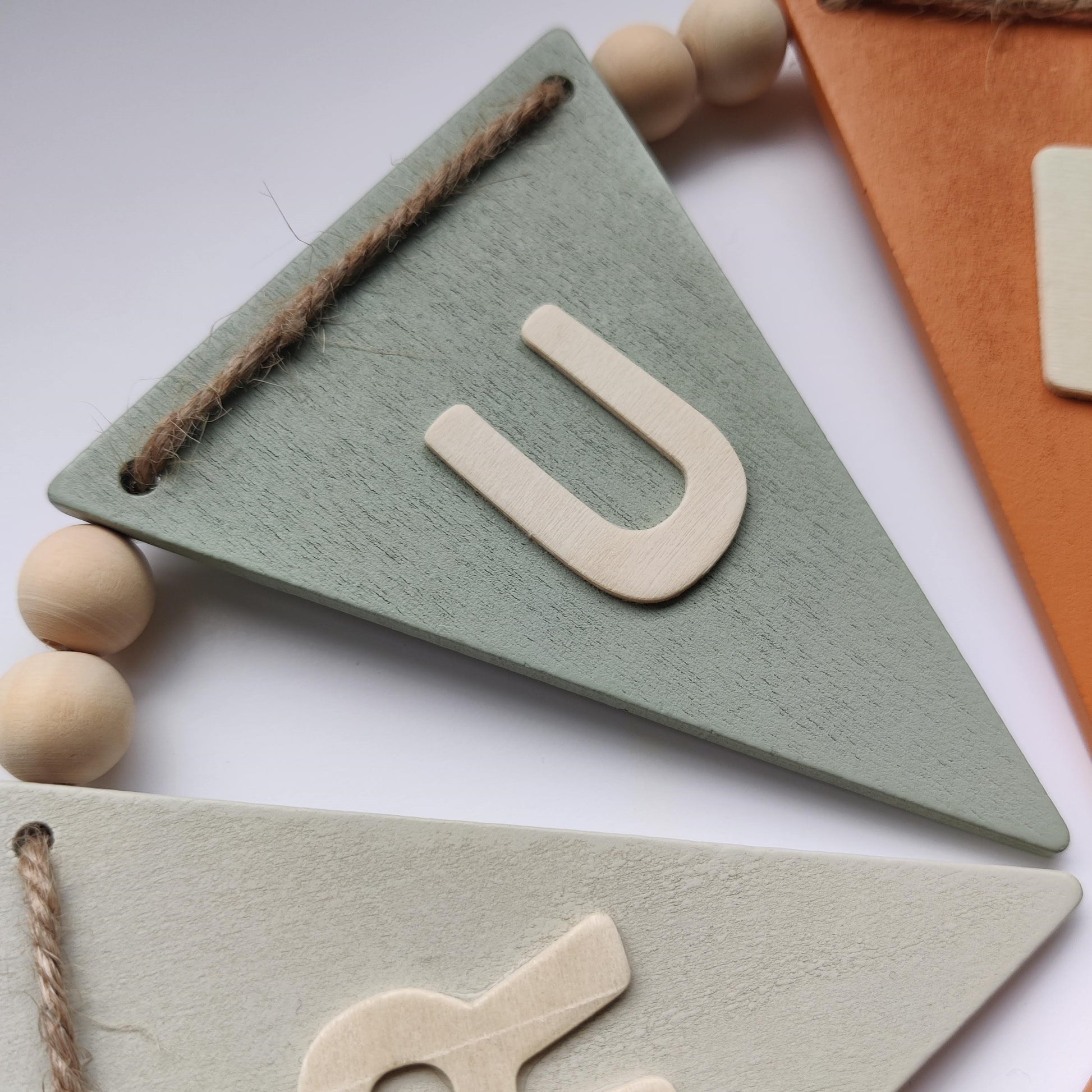 Close up of wooden bunting flag with neutral colour and the letter U