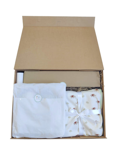 Image of open gift hamper contents on a white background, with tissue and ribbon-wrapped blanket visible