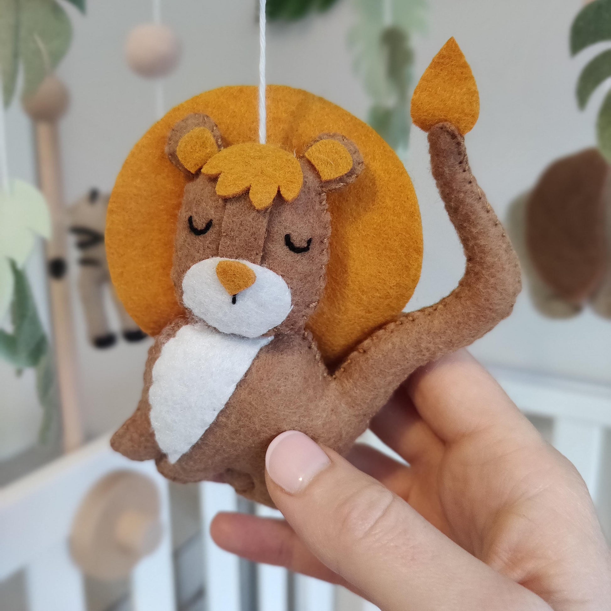 Felt orange and brown lion hanging on a cot mobile close up