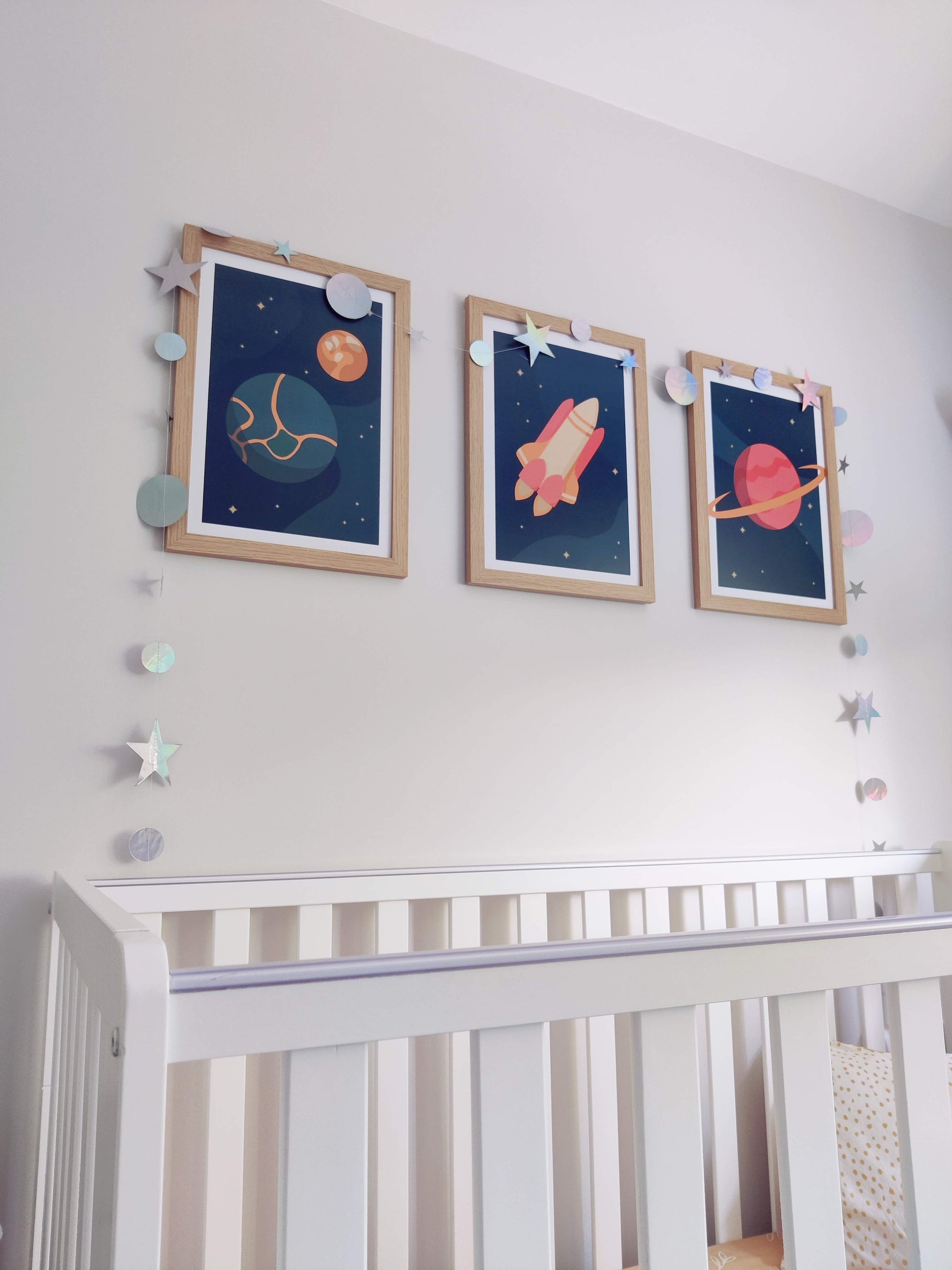 Low angle shot of space prints on the wall in a nursery with a crib in the foreground